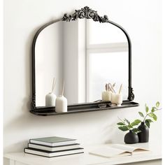 a mirror sitting on top of a white table next to a vase with candles in it