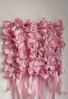 a pink wall hanging on the side of a white wall with lots of ribbons attached to it