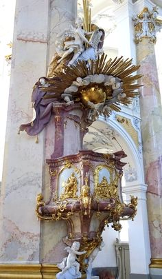 an ornate gold and purple clock in a church with angels on it's sides