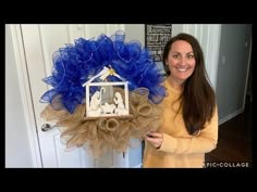 a woman holding up a wreath with nativity scene on it