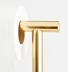 a gold toilet roll holder with two rolls of toilet paper on it's side