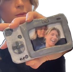 a woman holding up a camera to take a picture with her reflection in the mirror