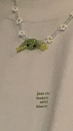 a white shirt with a green turtle on it's chest and beads around the neck