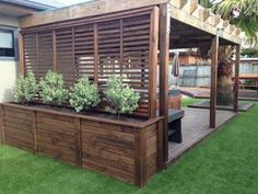 a wooden deck with planters on it in front of a building and grass area