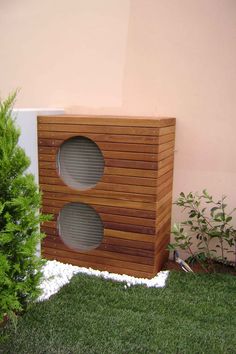 a wooden box sitting in the grass next to a tree and shrubbery with two speakers on it