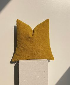 a yellow pillow sitting on top of a white block