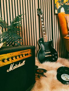 an electric guitar, amp and record player sit on a fur rug in front of a striped wall