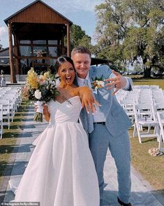 a bride and groom pose for a photo in front of white chairs