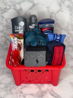 a red basket filled with items on top of a marble countertop next to a cup