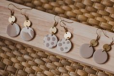 three pairs of earrings are hanging from a wooden holder on a wicker tablecloth