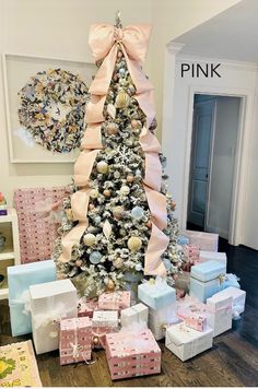 a christmas tree with presents under it and pink bows on the top is surrounded by other gifts