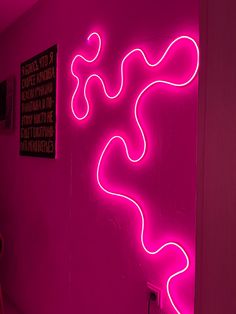 a pink wall with a neon sign on it