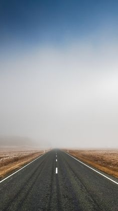 an empty road in the middle of nowhere on a foggy day with blue skies