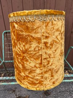 a large yellow hat sitting on top of a metal rack next to a wooden fence