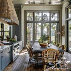 a large kitchen with lots of windows and wooden flooring, along with an island table surrounded by wicker chairs