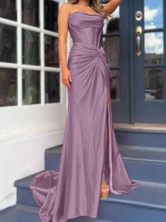 a woman in a long purple dress standing on steps with her hand on her hip