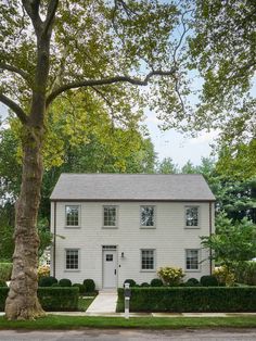 a white house surrounded by trees and hedges