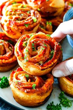 a hand is picking up some food from a plate with other small pastries on it