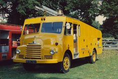 an old yellow truck is parked in the grass