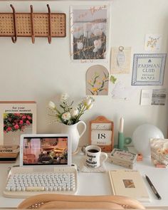 a white desk topped with a laptop computer sitting next to a cup of coffee and flowers