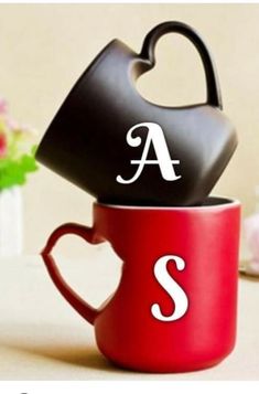 two coffee mugs with the letter s on them, one is black and one is red