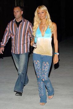 a man walking next to a woman in jeans and a striped shirt on the street