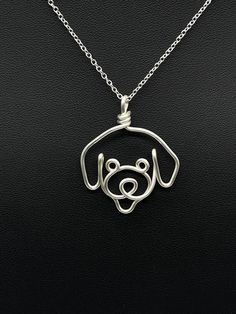 a necklace with a dog's face in the center on a black leather surface