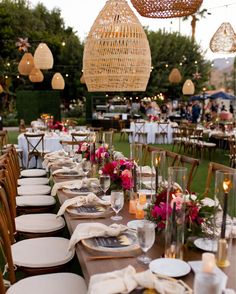 a long table is set with white plates and place settings for an outdoor dinner party