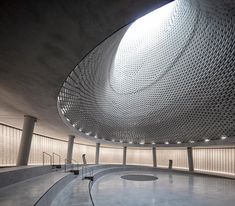 the inside of a building that has a circular ceiling and light coming from above it