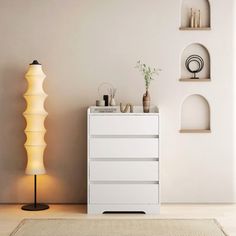 a white cabinet sitting in the middle of a room next to a lamp and shelves