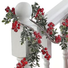 red berries and green leaves are hanging on the bannister railing with white posts