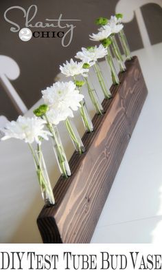 white flowers are arranged in the center of a long wooden stand on top of a table