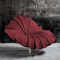 a red chair sitting on top of a metal stand in front of a black wall