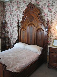 an old fashioned wooden bed in a room with floral wallpaper on the walls and floor