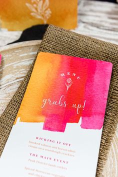 an orange and pink wedding card on top of burlock paper with the words grubs up