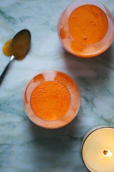 two glasses filled with liquid next to each other on a marble counter top and one has a spoon in it