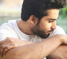 a man leaning his head on his hand while looking down at something in front of him