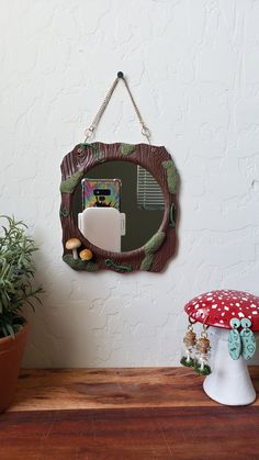 a mirror hanging on the side of a wall next to a mushroom shaped potted plant