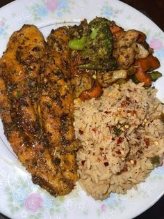 a white plate topped with chicken, rice and broccoli covered in seasoning