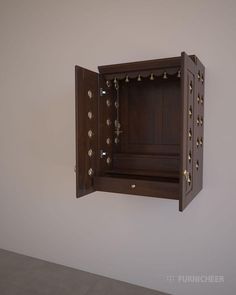 an open wooden box hanging from the side of a wall with brass studs on it