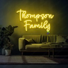 a neon sign that says,'thompson family'in front of a couch and potted plant