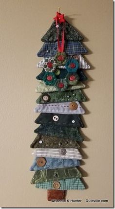 a christmas tree made out of different types of fabric and buttons on a wall hanging ornament