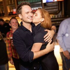 a man and woman embracing each other in front of a crowd at a bar with people standing around