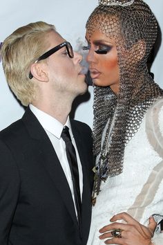 a man and woman kissing each other in front of a white backdrop