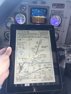 a person is holding up an ipad in the cockpit