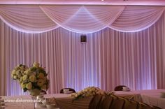 a table with flowers and chairs in front of a curtained wall at a wedding reception