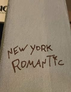 the word new york romantic written in brown ink on a white towel next to a toilet