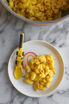 a plate with macaroni and cheese on it next to a measuring cup full of macaroni and cheese