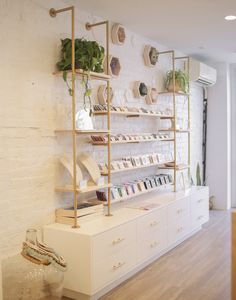 a white room with shelves filled with books and plant pots on the wall next to it