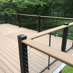 a wooden deck with metal railings in the middle and trees in the back ground